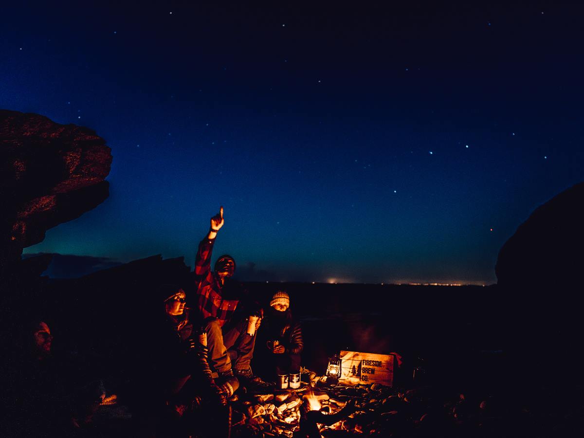 A fire on the North Devon coast at dusk — people gathered round it under a starlit sky